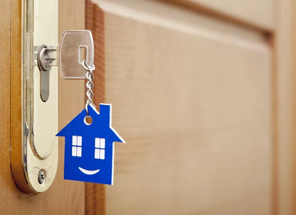 Una llave en una cerradura con icono de la casa con sonrisa en ella —  Fotos de Stock