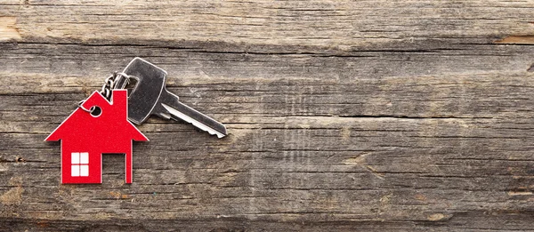 Symbol domu se stříbrným klíčem na vinobraní dřevěné pozadí — Stock fotografie