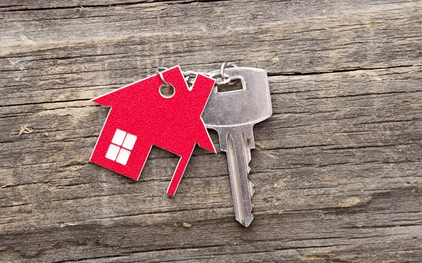 Símbolo de la casa con llave de plata sobre fondo de madera vintage — Foto de Stock