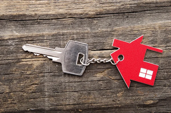 Símbolo de la casa con llave de plata sobre fondo de madera vintage —  Fotos de Stock