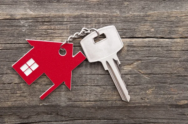 Símbolo de la casa con llave de plata sobre fondo de madera vintage —  Fotos de Stock