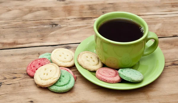 Tazza di tè con biscotti colorati e muffin marrone sul tavolo — Foto Stock