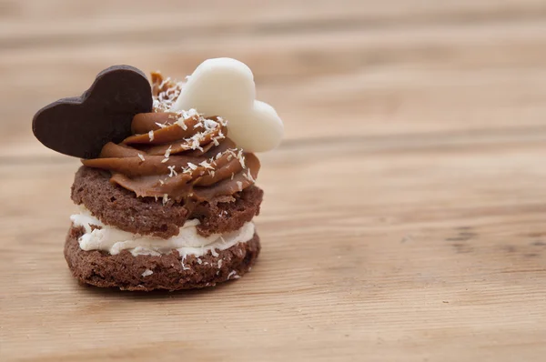 En cupcake på ett bord med två choklad hjärtan — Stockfoto