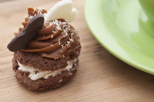 En cupcake på ett bord med två choklad hjärtan — Stockfoto