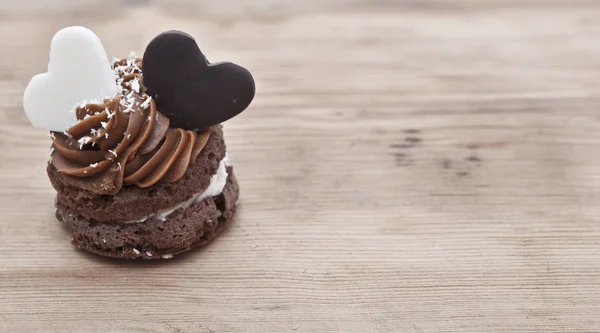 Кекс на столе с двумя шоколадными сердцами — стоковое фото