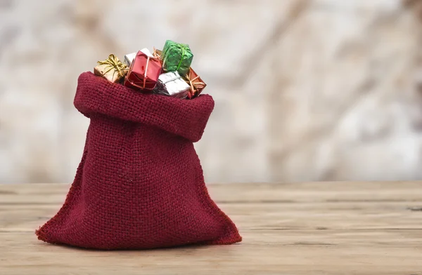 Kleurrijke geschenkdozen met linten en strikken, en rode zak op woode — Stockfoto