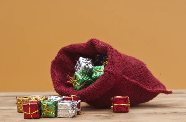 Scatole regalo colorate con nastri e fiocchi e sacco rosso su legno — Foto Stock