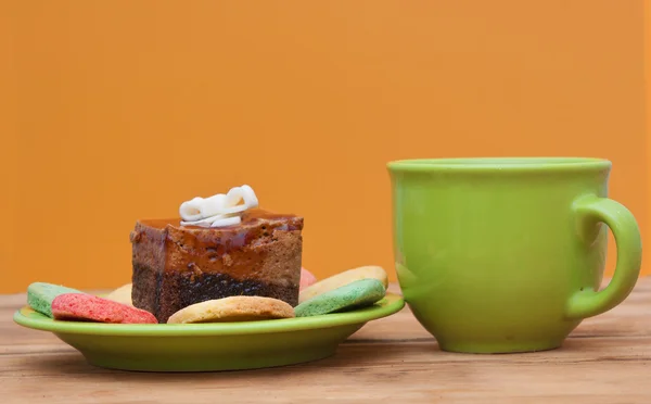 Színes cookie-k és barna muffin asztalra teáscsésze — Stock Fotó