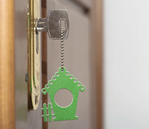 Una llave en una cerradura con icono de la casa con sonrisa en ella —  Fotos de Stock