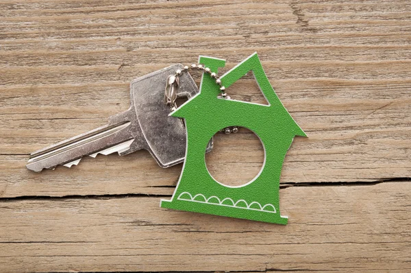 Símbolo de la casa con llave de plata sobre fondo de madera vintage —  Fotos de Stock