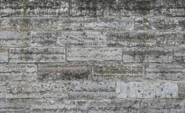 Koyu ve açık tonların belirgin dikey çizgileriyle sıkıntılı ve yaşlı bir görünüm sergileyen desenli, rengi solmuş beton bir duvar. Kirli dokuları, yıpranmış yüzeyleri, arka planları temsil eder.