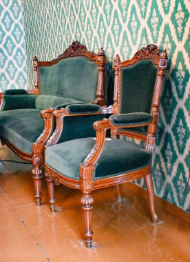 Gri bir duvar ve zemine karşı iki klasik koltuk. Boşluğu kopyala