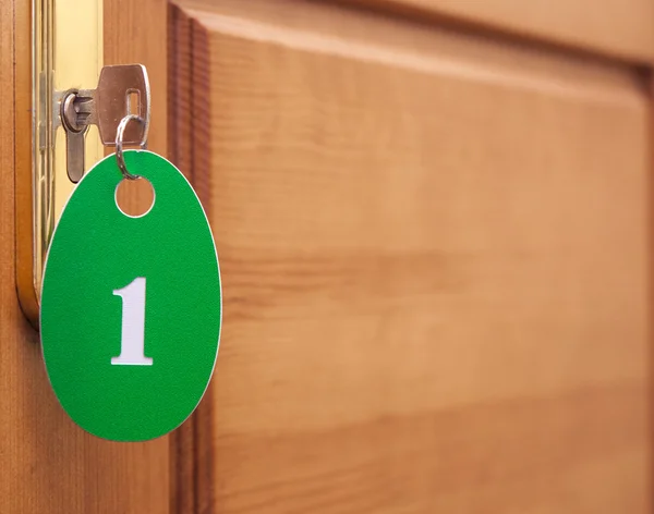 Türgriffe am Holzflügel der Tür und Schlüssel im Schlüsselloch mit Nummer — Stockfoto