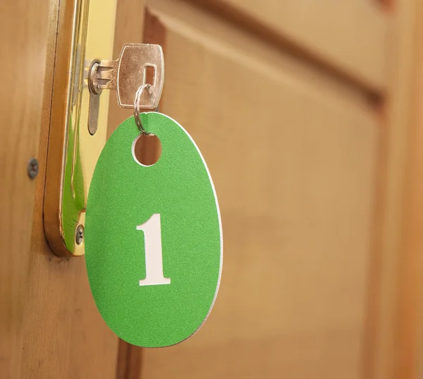 Door handles on wood wing of door and key in keyhole with number — Stock Photo, Image