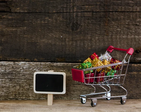 Trolley mit Geschenkboxen über Holzhintergrund — Stockfoto