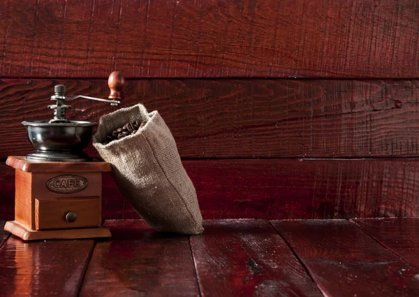 Koffiemolen met jute zak vol met geroosterde koffiebonen over w — Stockfoto