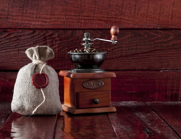 Кофейная мельница с мешком полный жареных кофейных зерен над W — стоковое фото