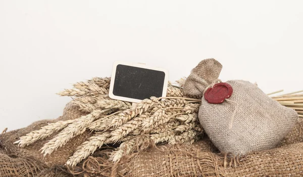 Orelhas de trigo e saco de grãos de trigo em backgroun de madeira marrom — Fotografia de Stock
