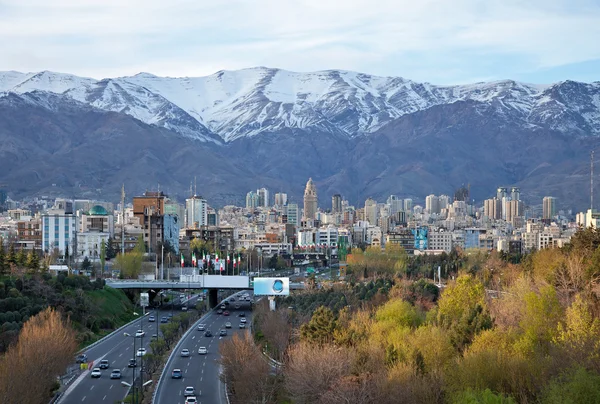 Línea del horizonte de Teherán y autopista frente a las montañas nevadas —  Fotos de Stock