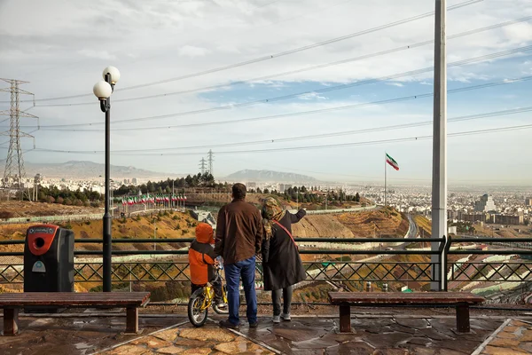 Familia iraní con su hijo en bicicleta mirando el horizonte de Teherán desde un parque de altura Imagen de stock