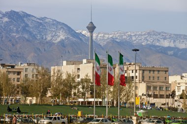 Milad Kulesi ve çerçeve içinde Iran bayrakları ile Tahran şehir