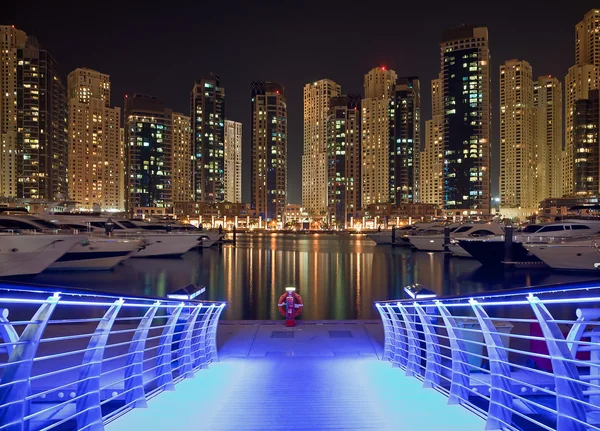 Dubai Marina at Night with Illuminated Blue Pier and Reflection of Building on the Water — стоковое фото