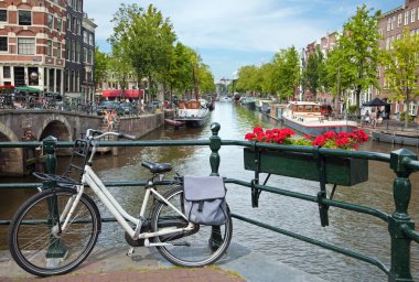 Mavi gökyüzü karşı Amsterdam'da bir kanala bakan köprüdeki Beyaz Bisiklet