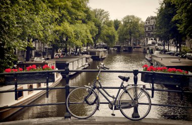 Amsterdam'da bir kanala bakan yaya köprüsü üzerinde park etmiş Bisiklet
