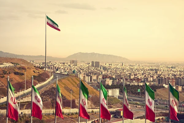 Fila de banderas de Irán frente al horizonte de Teherán —  Fotos de Stock