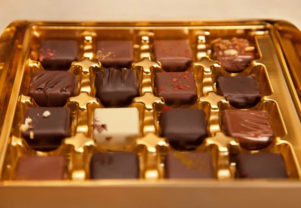 Golden Box of Square Shaped Chocolates in Different Colors and Types Stock Picture