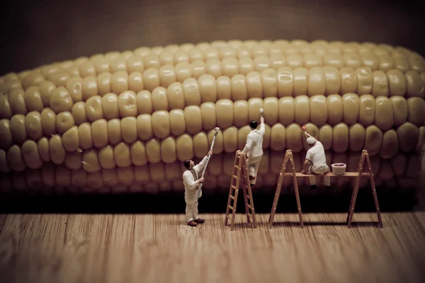 Miniature painters coloring corn on the cob — Stock Photo, Image