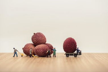 Miniature movers loading lychees on truck clipart