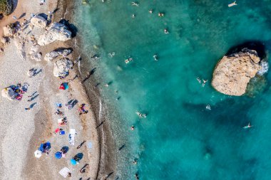 Kıbrıs Rum Kesimi 'nin Afrodit Kayası' nda yüzen ve güneşlenen turistler