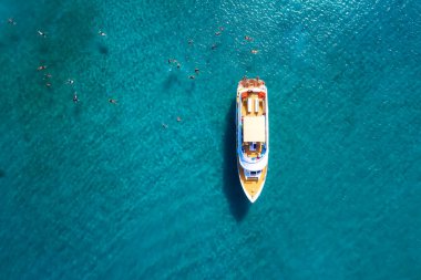 Yanında yüzen turistlerle deniz gezisi teknesi.