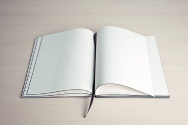 Tahta masanın üstünde boş sayfalar olan açık bir kitap.