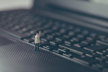 üstünde tepe-in belgili tanımlık laptop sallayarak minyatür işadamı. iş kavramı