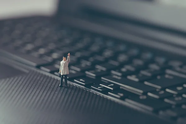 Un uomo d'affari in miniatura che saluta sopra il portatile. Concetto aziendale — Foto Stock