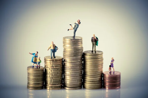 Concepto de presupuesto alegremente. Familia en miniatura sobre pila de monedas . — Foto de Stock