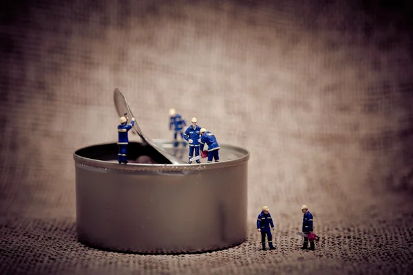 Group of miniature workers opening a can. Color tone tuned macro — Stock Photo, Image