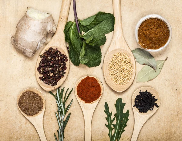 Various spices on kitchen spoons on grunge table — Stock Photo, Image