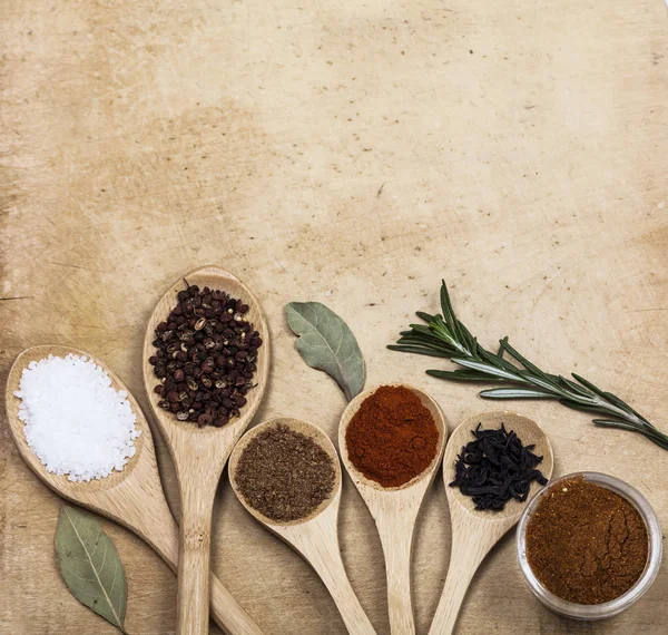 Various spices on kitchen spoons on grunge table — Stock Photo, Image