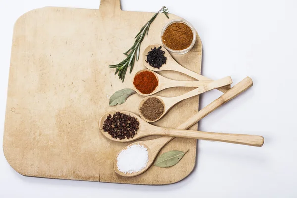 Colorful spices and spoons on cutting board — Stock Photo, Image