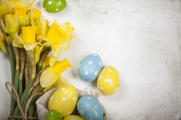 Pasen achtergrond met beschilderde eieren en bloeiende narcissen — Stockfoto