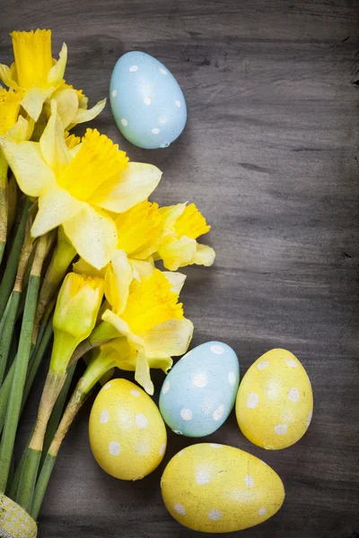 Kleurrijke paaseieren en voorjaar narcissen op achtergrond papier — Stockfoto