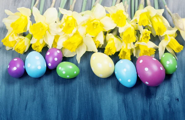 Colorful Easter eggs and spring daffodils on paper background — Stock Photo, Image