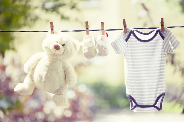 Babybekleidung, Stiefel und Teddy hängen an der Wäscheleine — Stockfoto