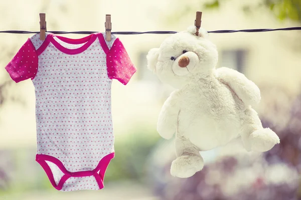 Baby clothes and teddy bear hanging on the clothesline — Stock Photo, Image