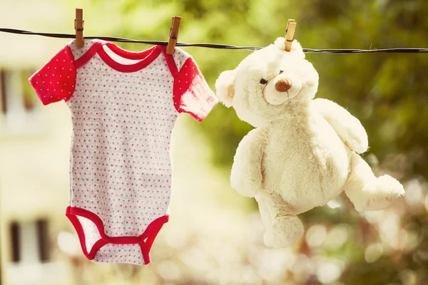 Baby clothes and teddy bear hanging on the clothesline — Stock Photo, Image