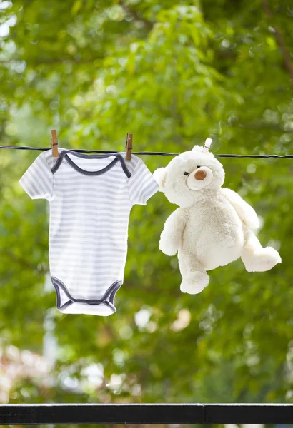 Baby clothes and teddy bear hanging on the clothesline — Stock Photo, Image