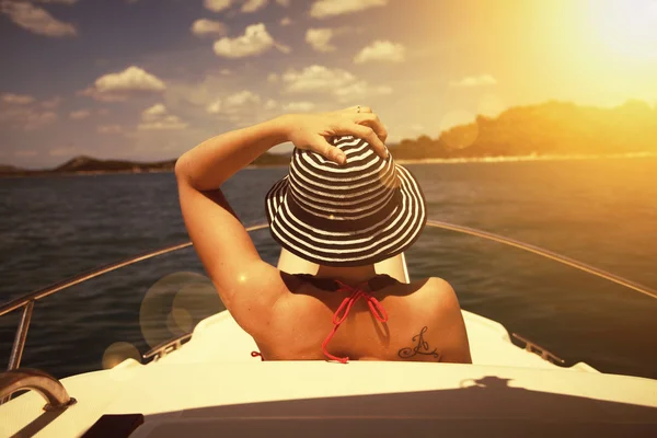 Młoda kobieta w kapeluszu siedzi z przodu łódź żagiel — Zdjęcie stockowe